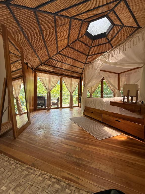 a bedroom with a bed in a room with wooden floors at SeTena Tierra Humeda Ecolodge in Minca