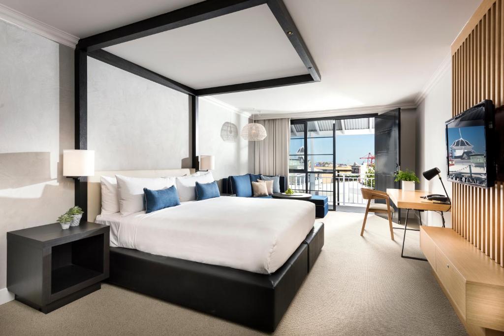 
a hotel room with a large bed and a large window at Tradewinds Hotel and Suites Fremantle in Fremantle
