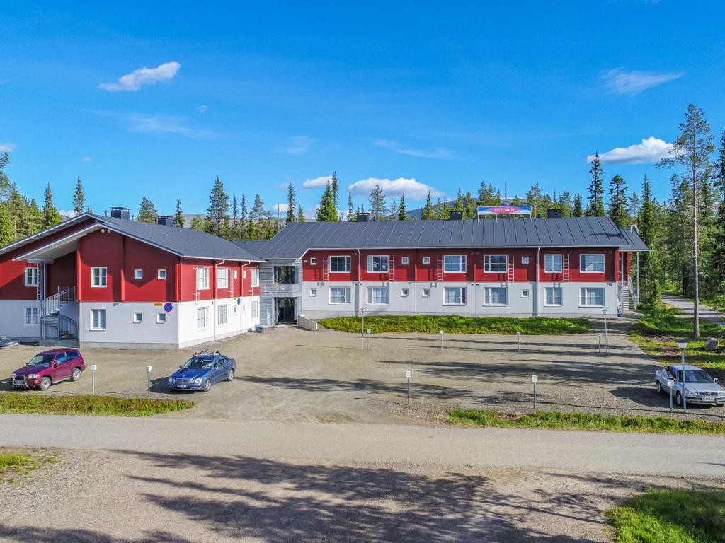 a large red and white building with cars parked in a parking lot at Holiday Home Yllästar 3 as 508 by Interhome in Äkäslompolo
