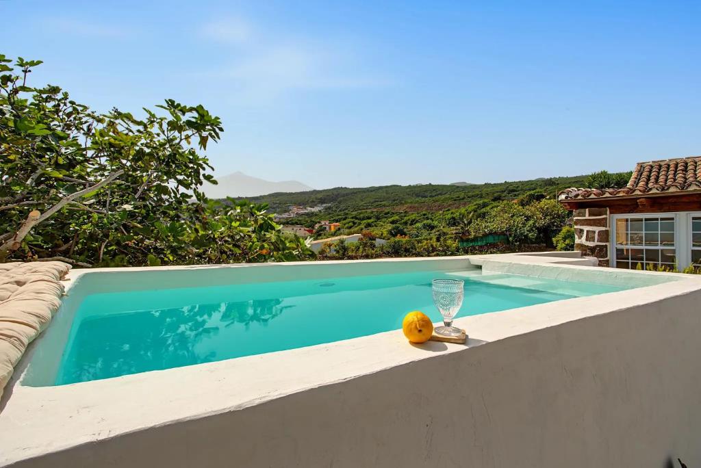 a swimming pool with a glass of wine and a drink on the edge at La Paredita Casa Acentejo in Tanque