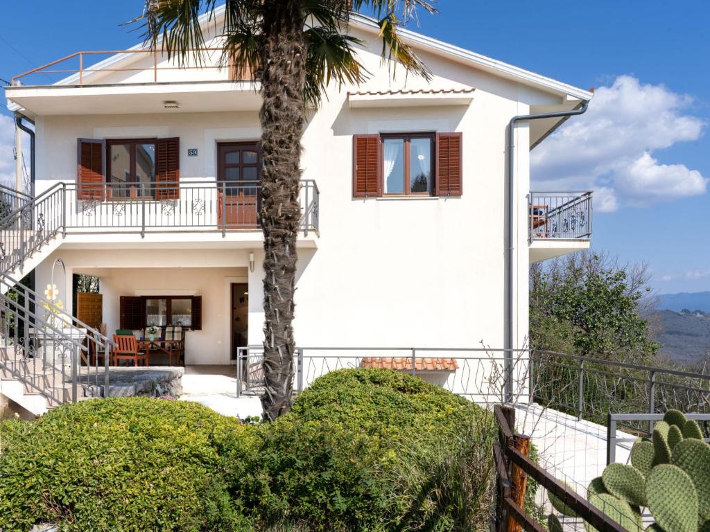 a white house with a palm tree in front of it at Holiday Home Orbani by Interhome in Lovran