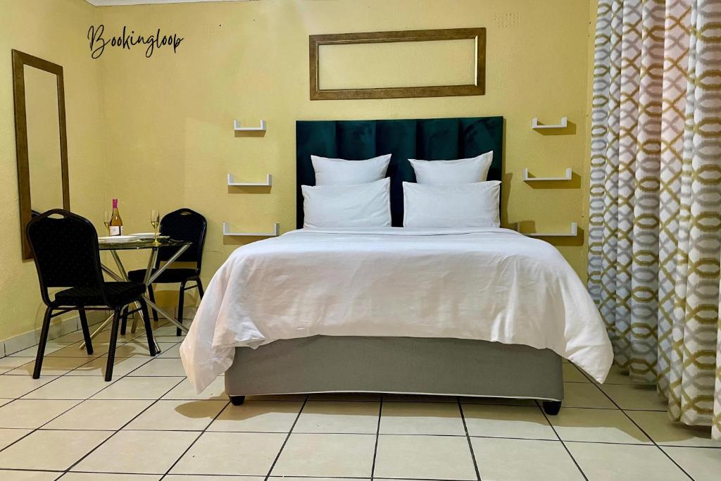 a bed with white sheets and pillows in a room at Budget Stays at Olivia Pines Guesthouse in Krugersdorp