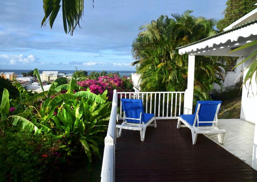 two blue chairs on a porch with a view of the ocean at LE LAGON BLEU, BUNGALOWS Vue sur MER , 350 m de la plage in Sainte-Anne