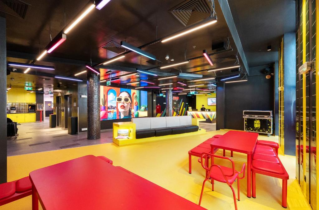 a room with red tables and chairs and a couch at AMISTAT Hub Hostel Budapest in Budapest