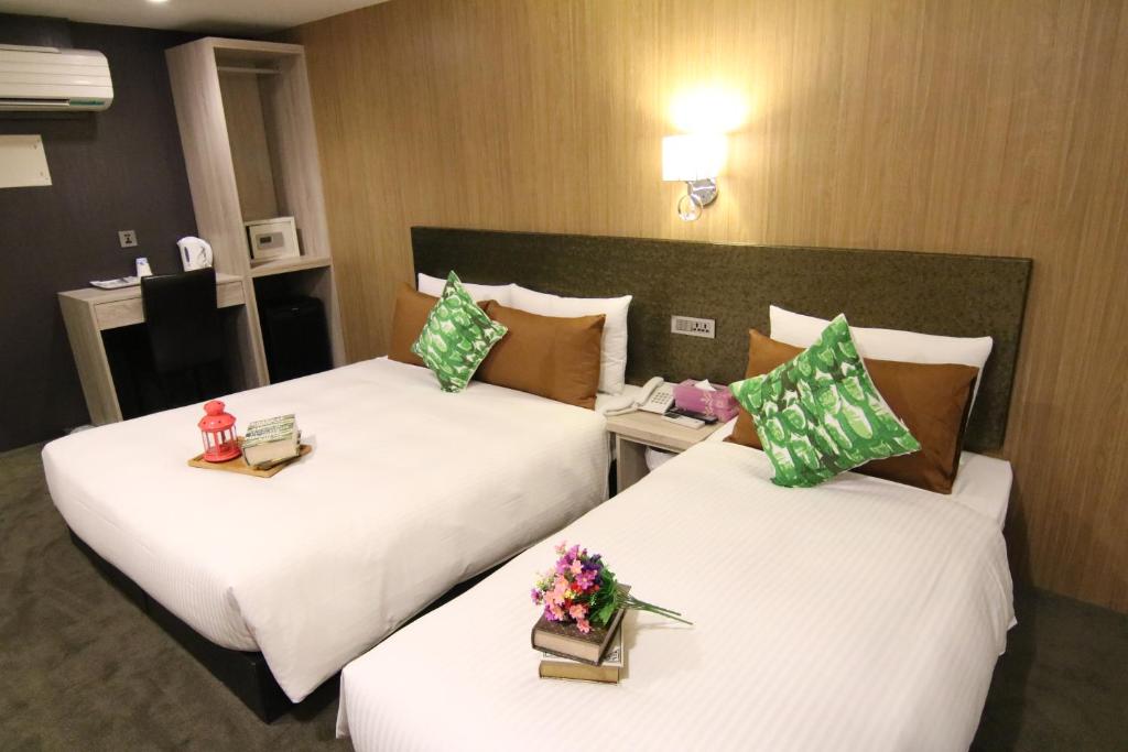 two beds in a hotel room with flowers on them at Hotel 6 - Wannien in Taipei