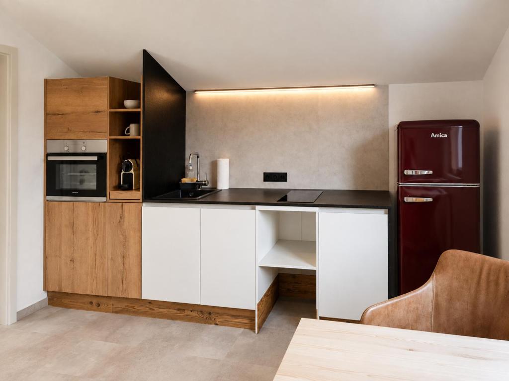 a kitchen with white cabinets and a black refrigerator at Toms ONE in Saalfelden am Steinernen Meer