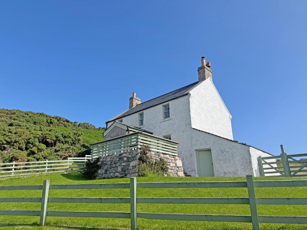 a house on a hill with a fence in front of it at The Cottage in Rispond