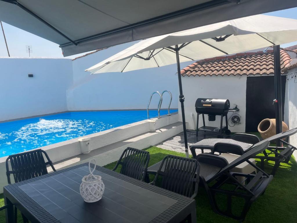 a patio with a table and chairs and a swimming pool at El Refugio de Navalcuervo 