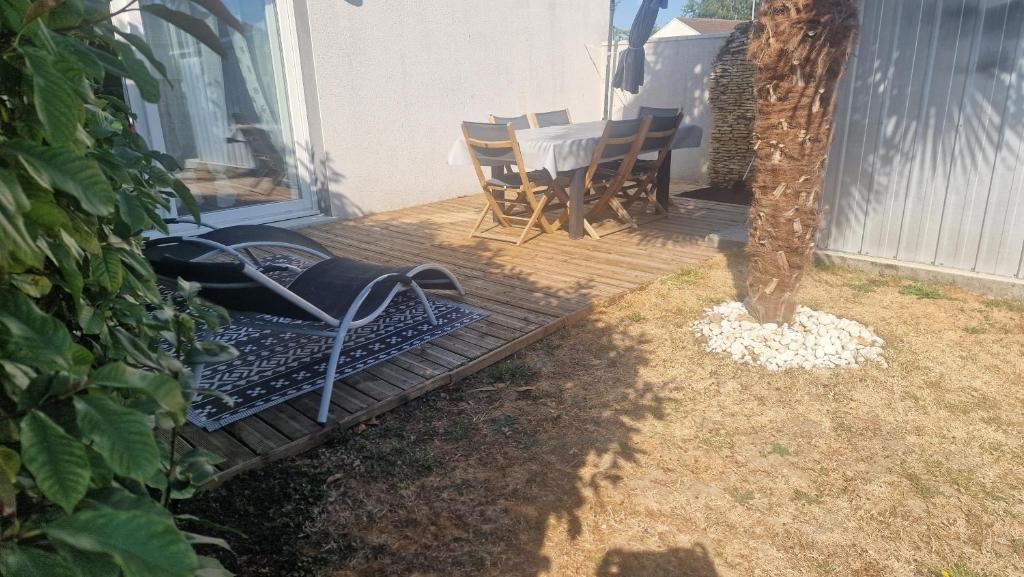 a wooden deck with a table and chairs on it at Maison le palmier in Troarn