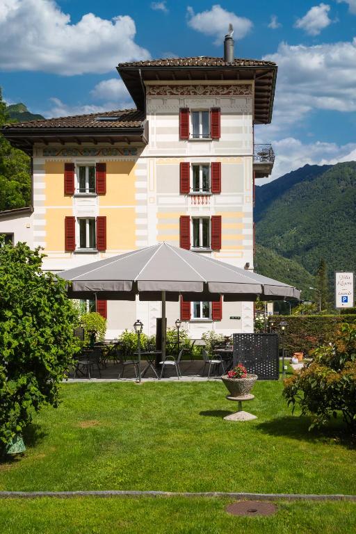 a large building with an umbrella in front of it at Locanda Villa d' Epoca in Aurigeno