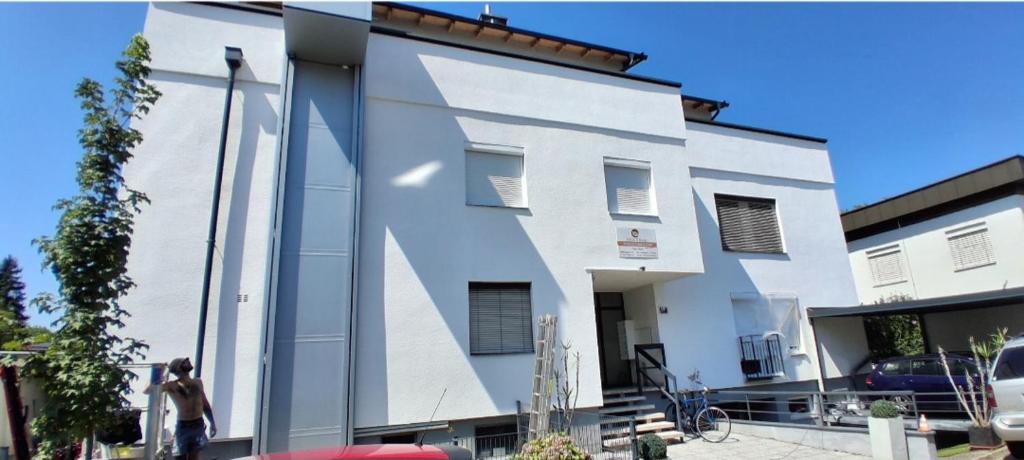 a white building with a woman standing in front of it at Paul's Home in Klagenfurt