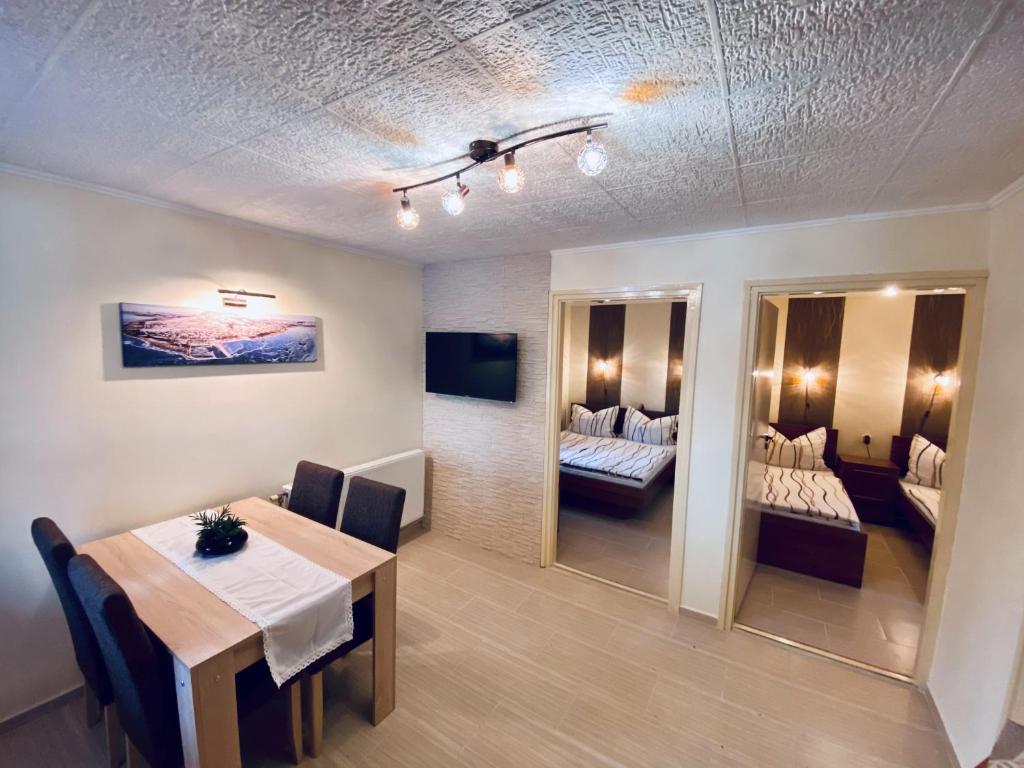 a dining room with a table and a room with beds at Bungalow Park Balatonboglár in Balatonboglár