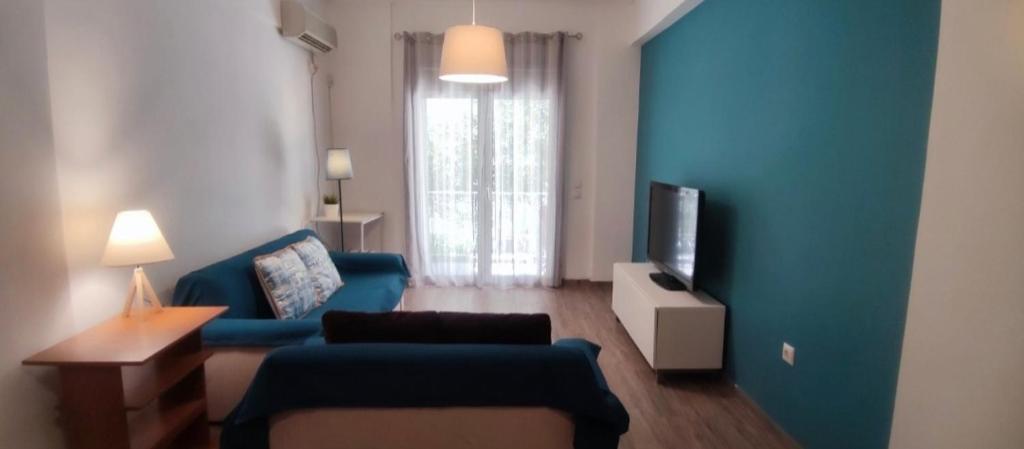 a living room with a blue couch and a tv at Loutraki by the sea in Loutraki