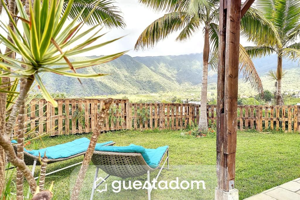 a hammock in a yard with palm trees and a fence at Le Yucca - Terrasse et jardin - Wifi in Saint-Louis