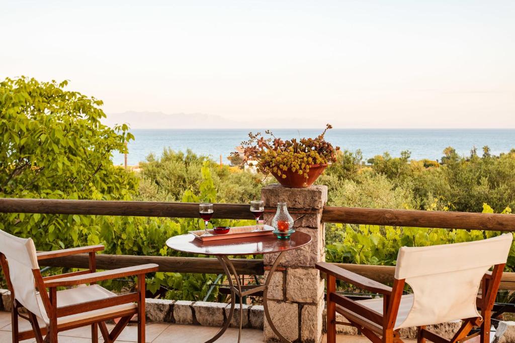 a table and chairs on a balcony with a view of the ocean at Petalidi Olive Garden Stone House near the beach in Petalidi