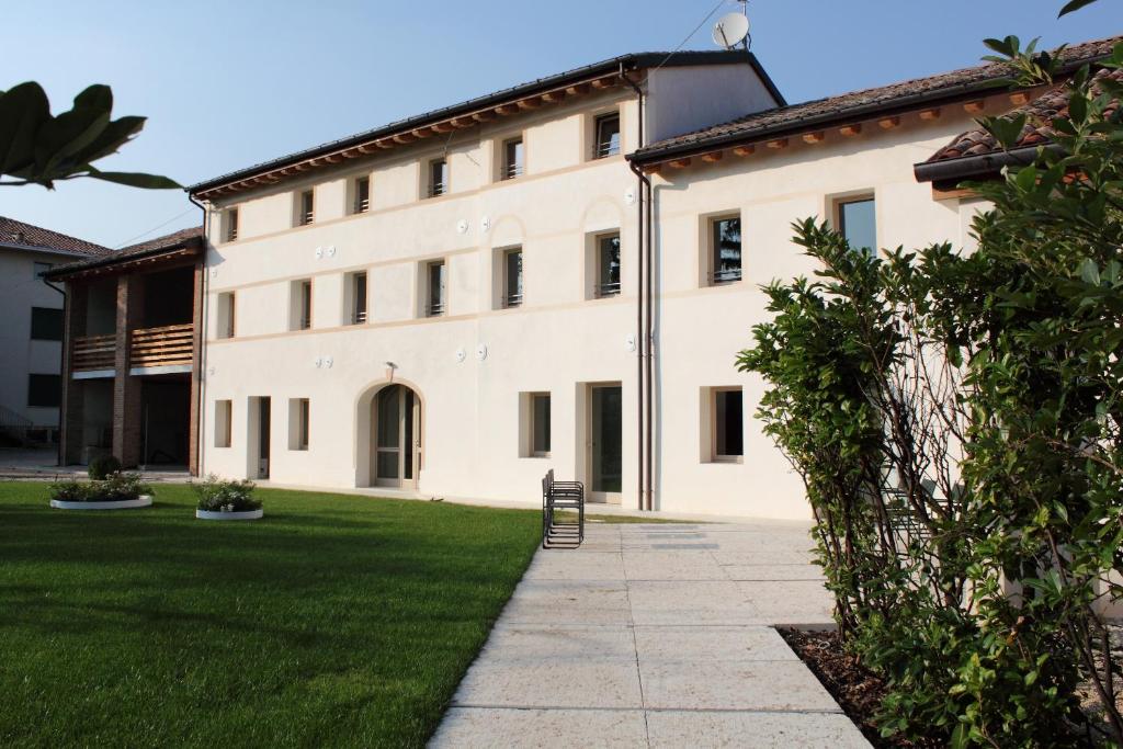 un grande edificio bianco con una sedia nel cortile di Caspineda Agriturismo a Montebelluna