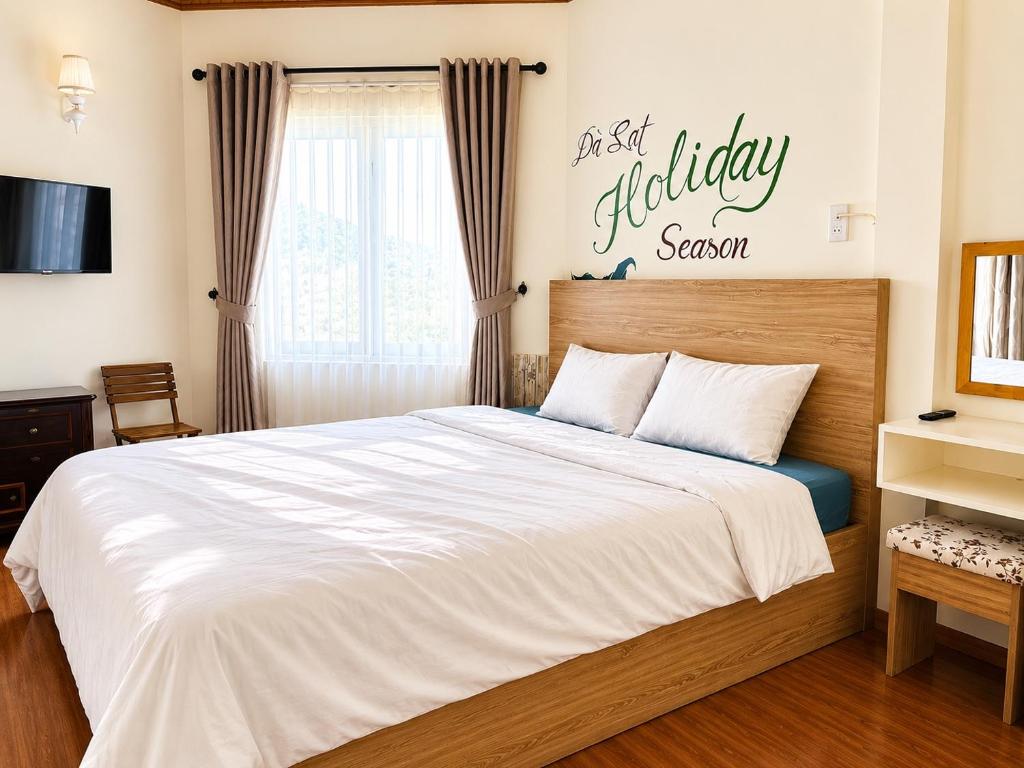 a bedroom with a bed with a happy holiday sign on the wall at Nhà Của Thỏ Vân Anh in Da Lat