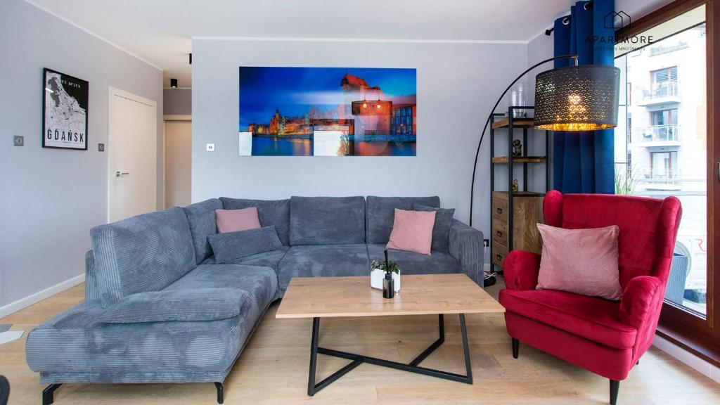 a living room with a blue couch and a red chair at City Center - AURA by Apartmore in Gdańsk
