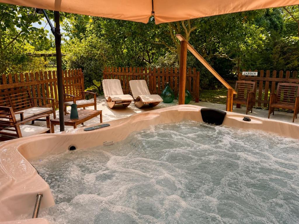 a hot tub in a backyard with chairs and an umbrella at Podere Cafasso Country House in Paestum