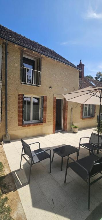 a patio with two chairs and a table and an umbrella at Au fil de la Cisse in Molineuf