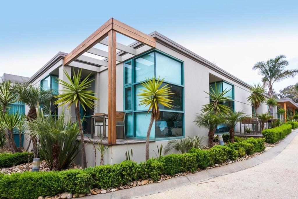 a house with large windows and palm trees at Anglesea River Apartment 22 in Anglesea