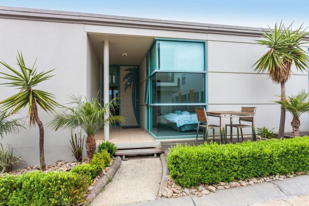 a house with a table and chairs and palm trees at Anglesea River Apartment 23 in Anglesea
