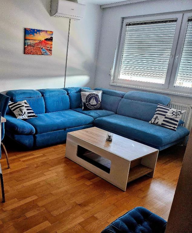 a blue couch in a living room with a coffee table at Apartman Dona in Bosanska Gradiška