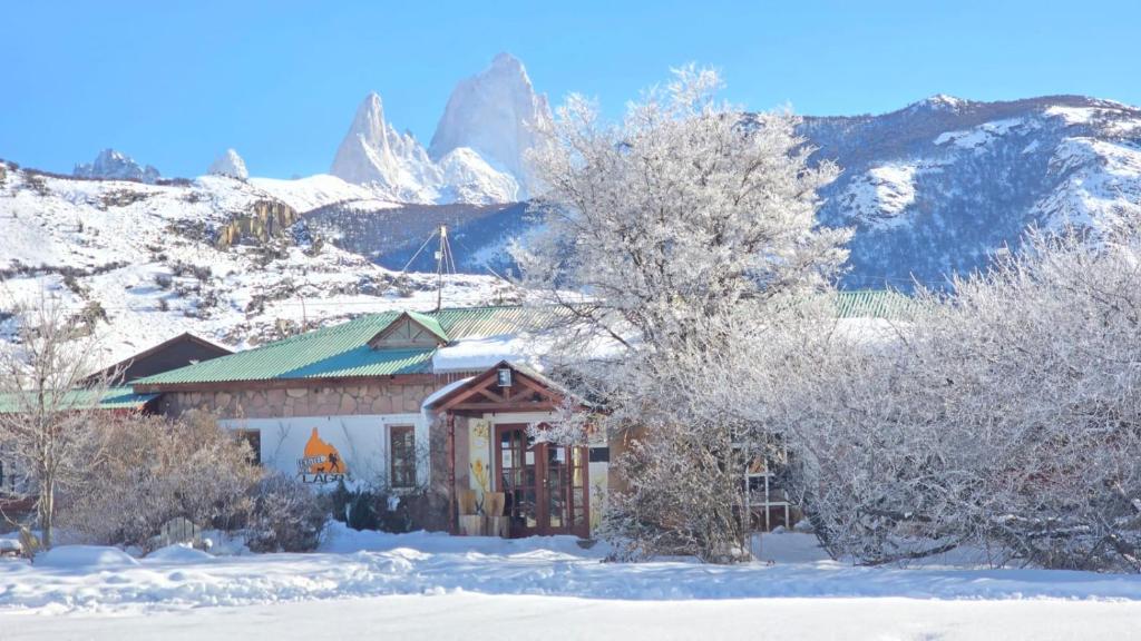 a house in the snow with mountains in the background at Hostel del Lago, habitaciones privadas y cabañas in El Chalten