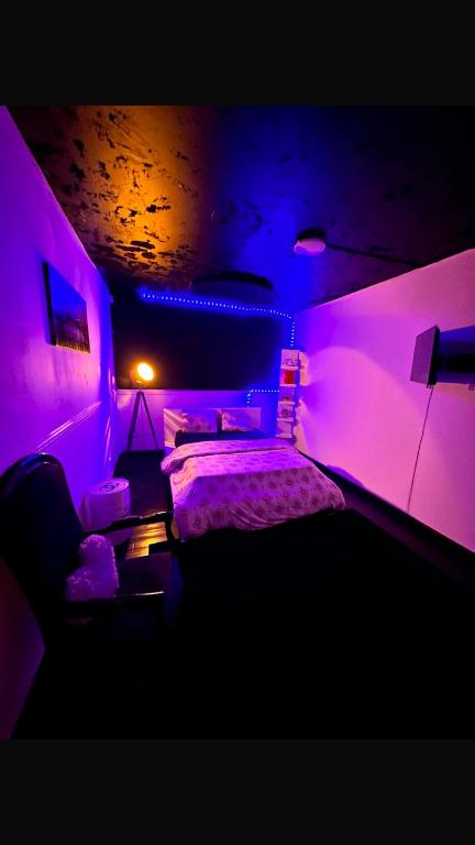a bedroom with a bed with purple lights at DouceNuits in Le Blanc-Mesnil