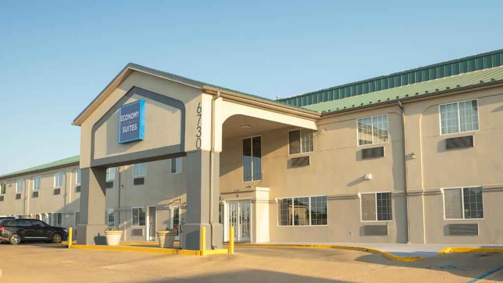a building with a car parked in front of it at Economy Suites - Tulsa Airport in Tulsa