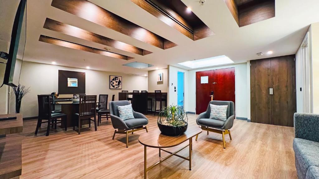 A bright hotel lounge with armchairs, a coffee table and a dining area.