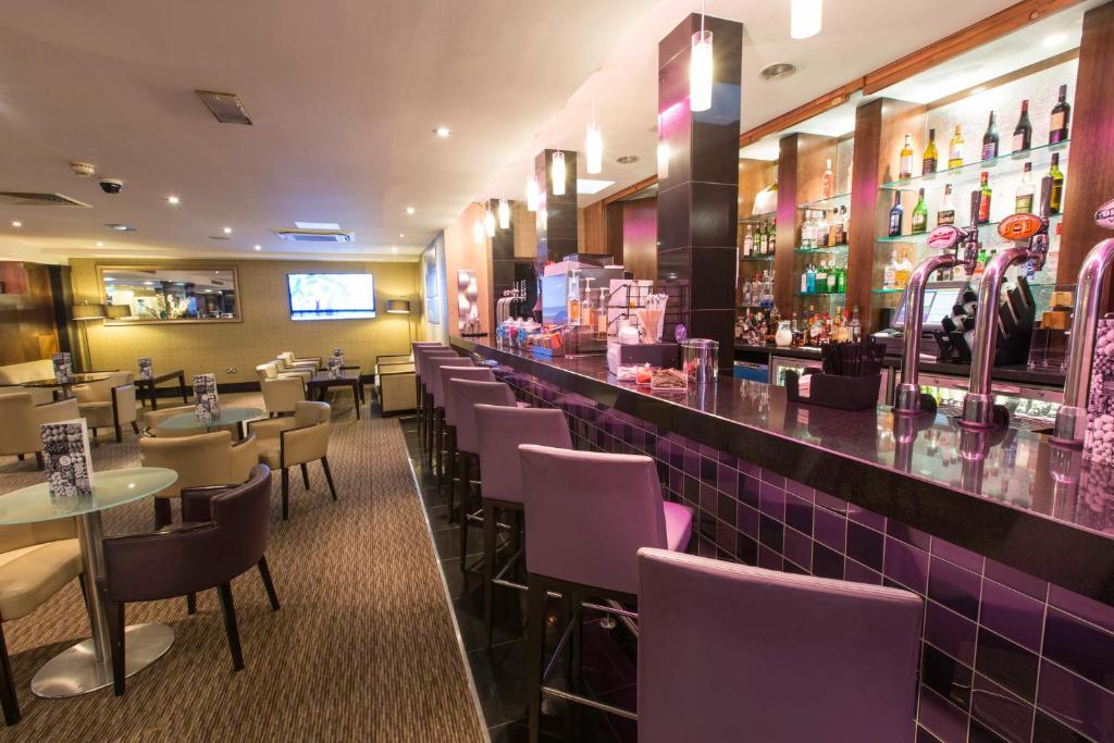 a restaurant with purple chairs and a bar at Crowne Plaza London Ealing by IHG in London