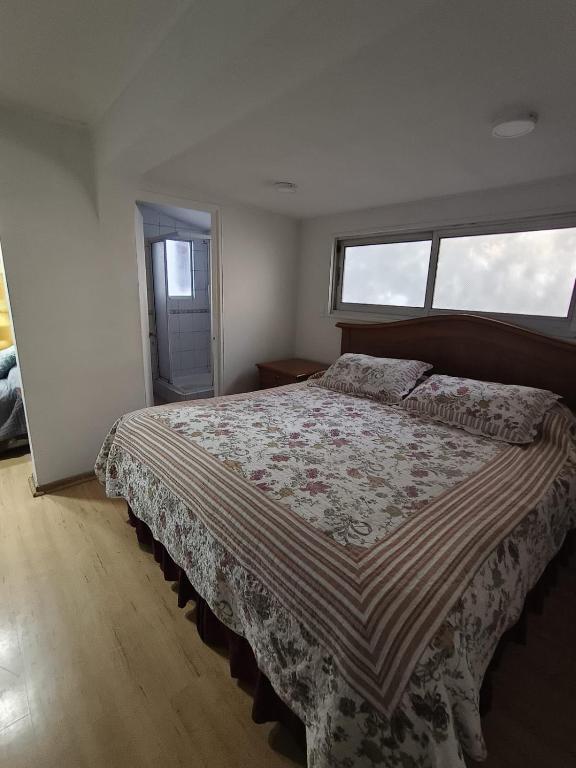 a bedroom with a large bed with a floral bedspread at Hostal 7 norte Sporting viña del mar in Viña del Mar