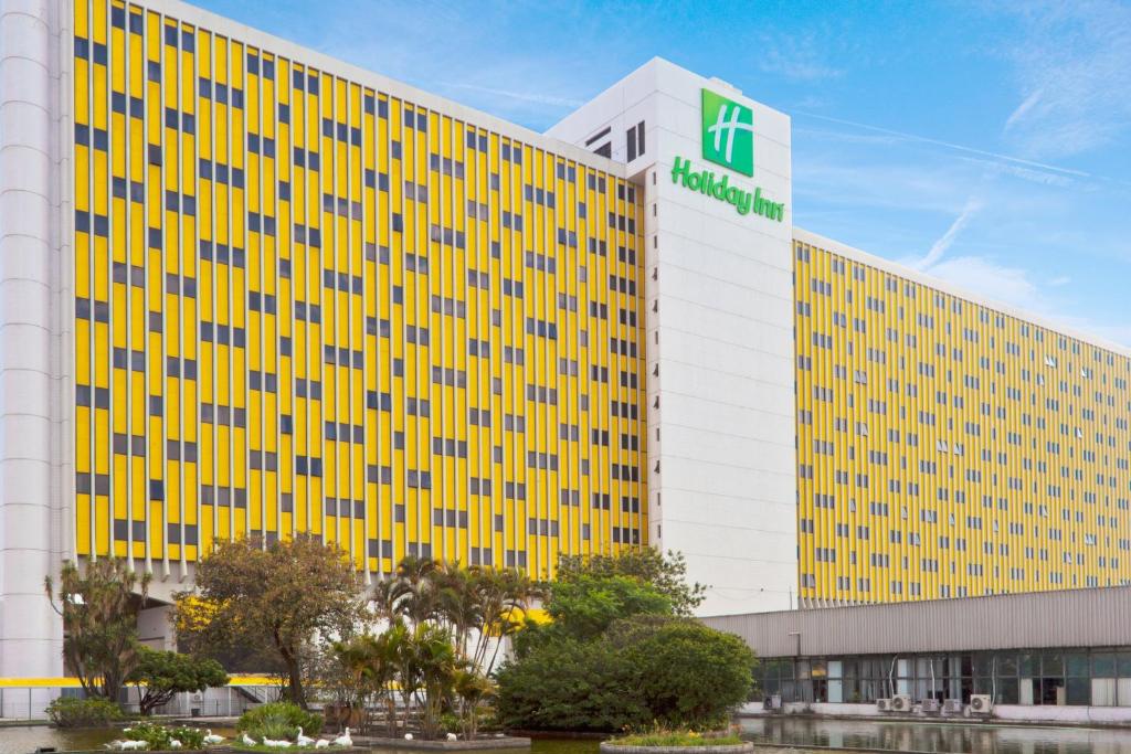 a large yellow building with a green sign on it at Holiday Inn Sao Paulo Parque Anhembi by IHG in São Paulo