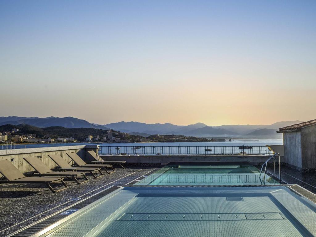 a swimming pool on the roof of a building with chairs at ibis Styles Ajaccio Napoleon in Ajaccio