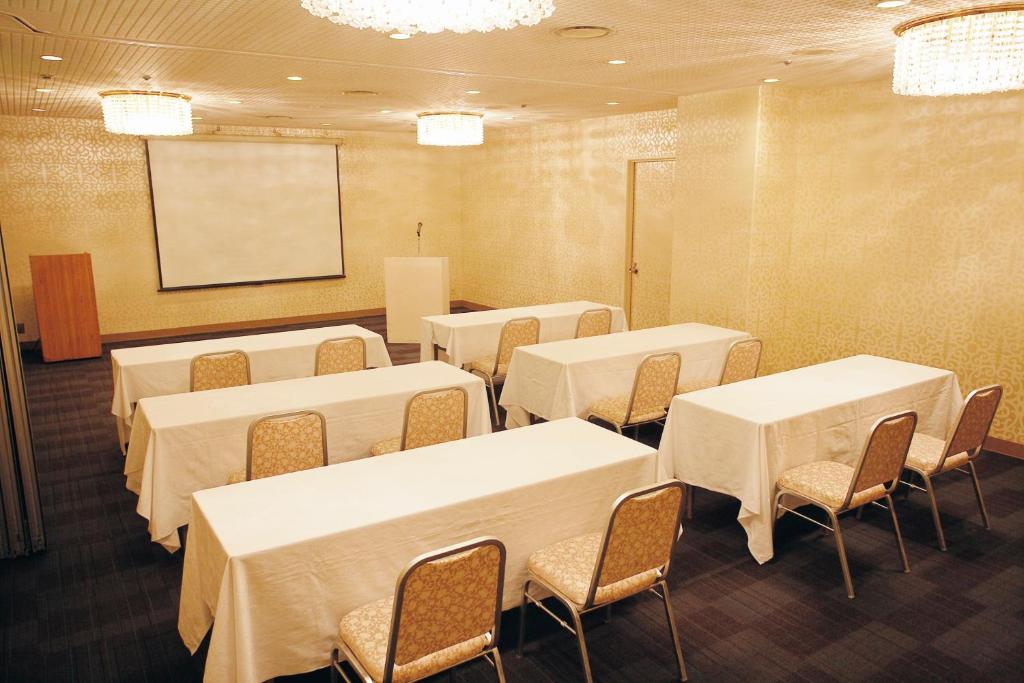 a conference room with tables and chairs and a screen at ANA Crowne Plaza Kochi by IHG in Sagamichō