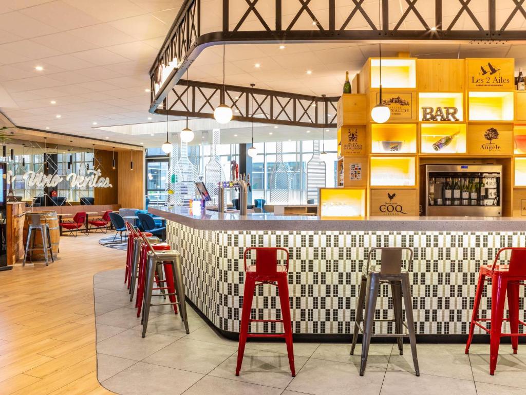 a bar in a restaurant with red stools at ibis Paris CDG Airport in Roissy-en-France