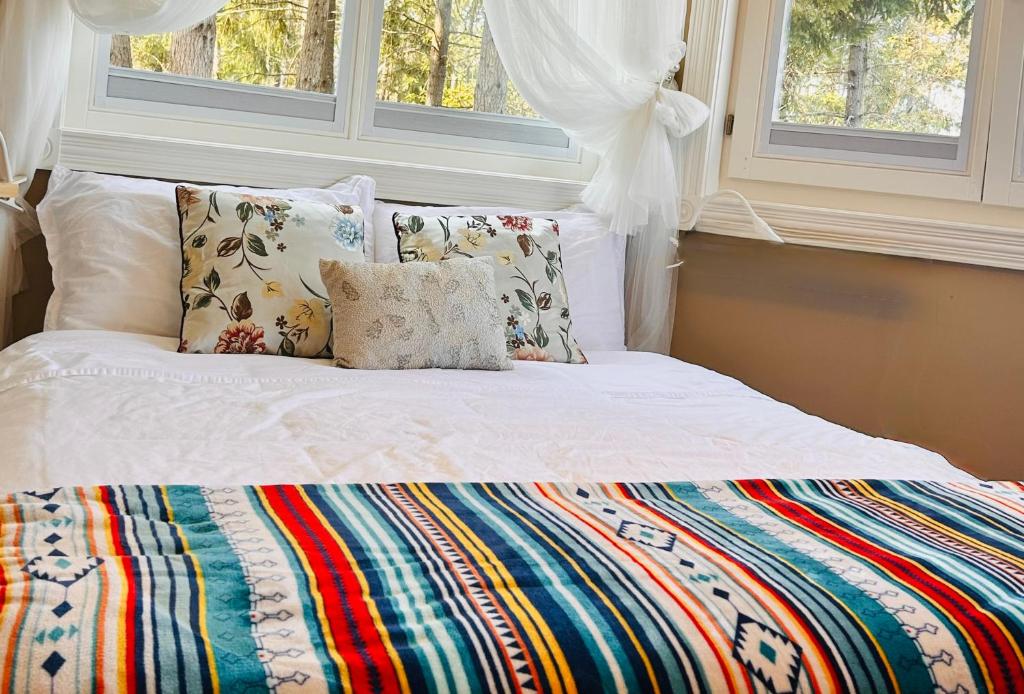 a bed with a colorful blanket and pillows on it at Shambhala Retreat-Zen Suite in Nanoose Bay