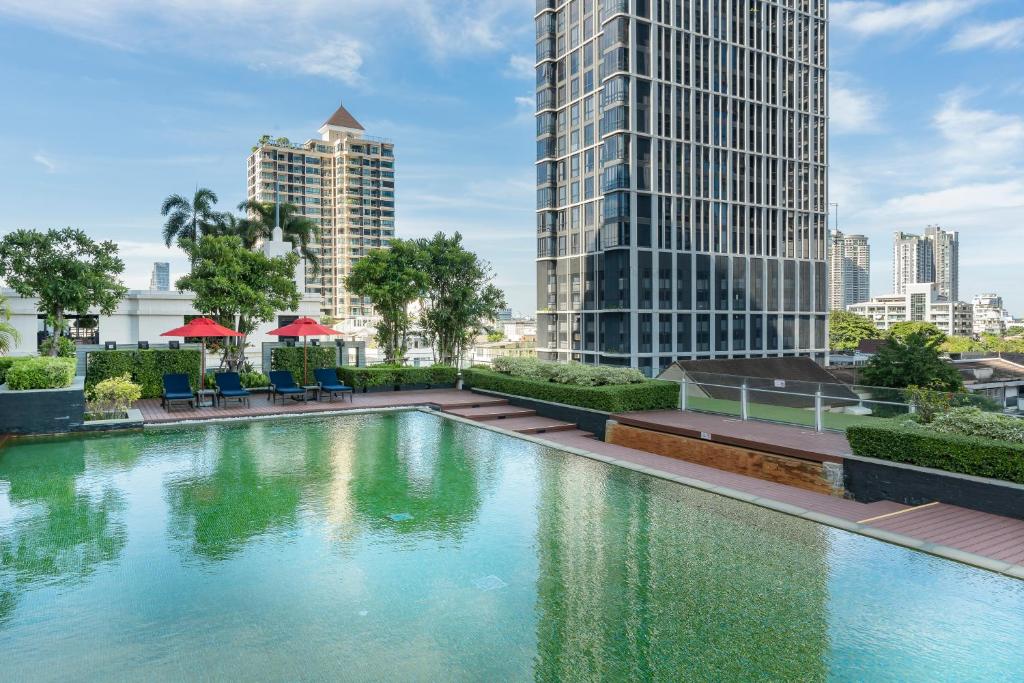A rooftop-looking outdoor pool with open skyline views and surrounding greenery.