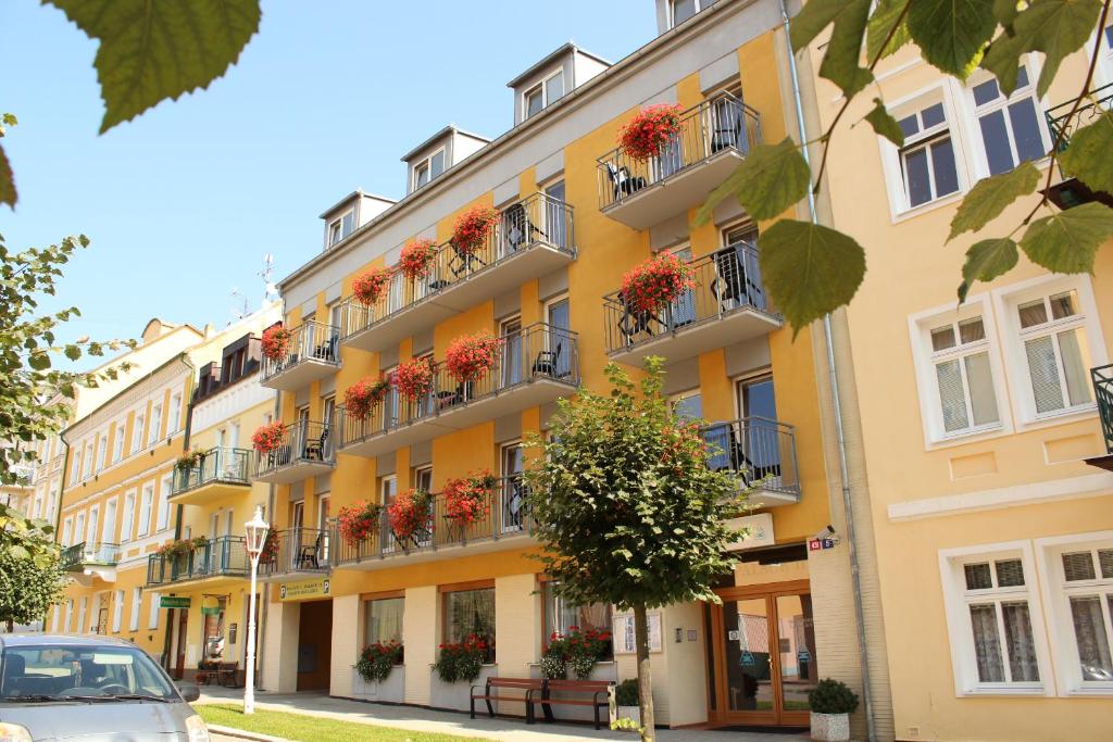 a yellow building with flower boxes on the balconies at LD PALACE II Spa & Kur in Františkovy Lázně
