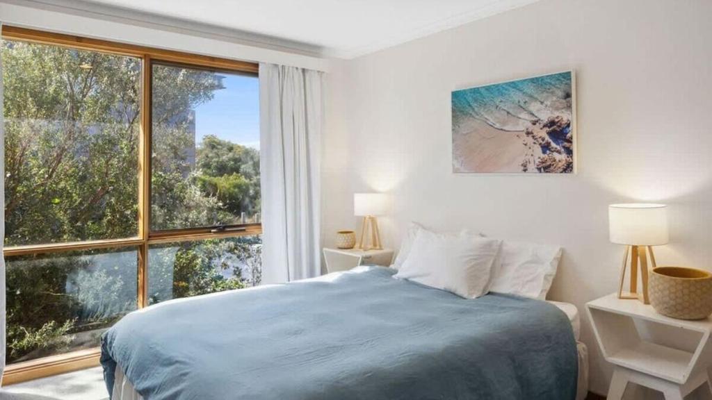 a white bedroom with a bed and a large window at Ocean Ridge House Fairhaven in Aireys Inlet