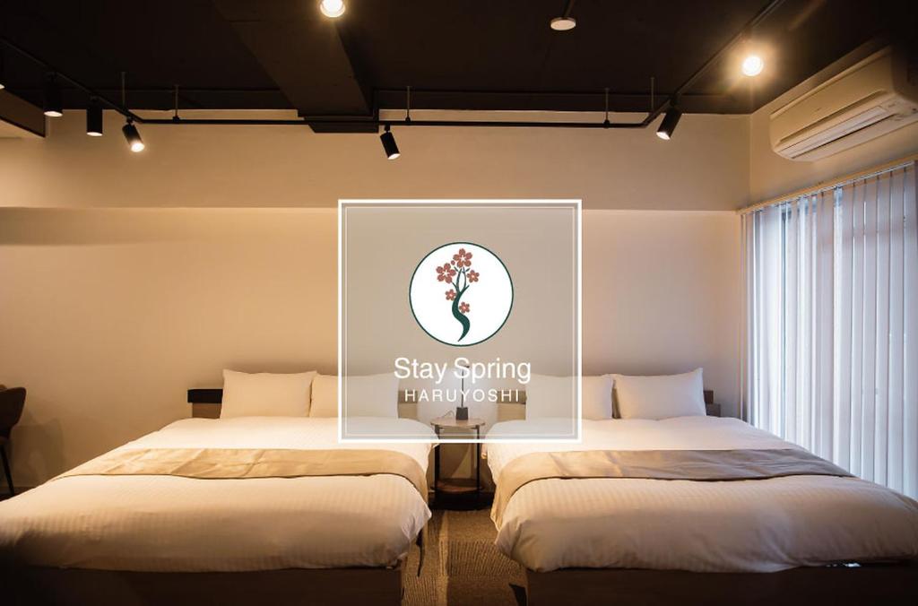 two beds in a room with a picture on the wall at StaySpring HARUYOSHI in Fukuoka