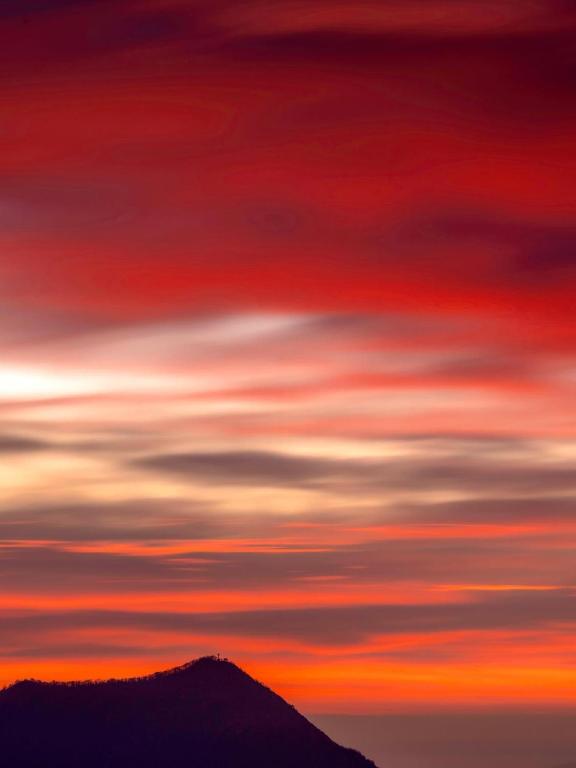 a sunset sky with clouds over a mountain at La Tana del Ghiro in Condove