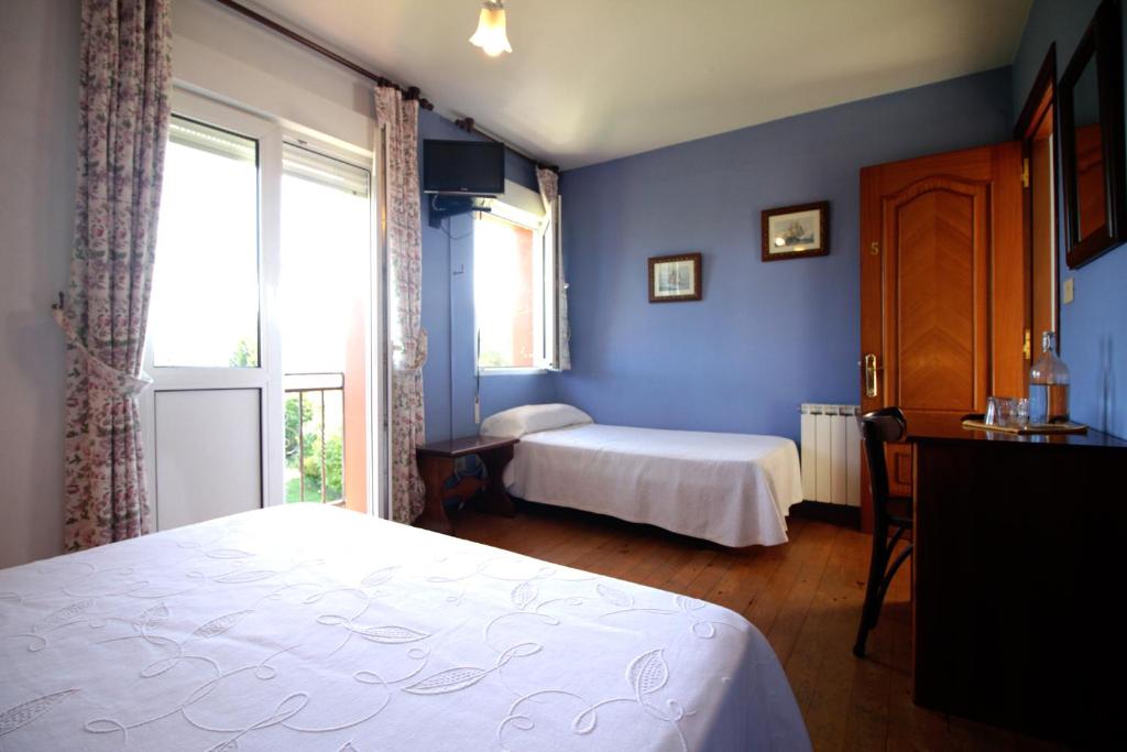 a bedroom with blue walls and a bed and a window at Hotel Rural Alavera in San Martin del Mar