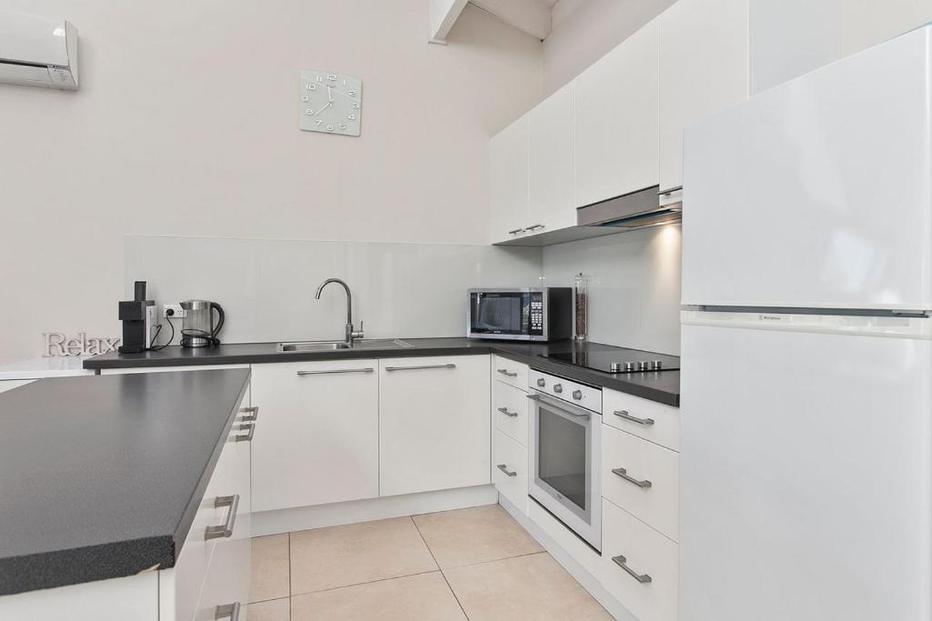 a kitchen with white cabinets and a black counter top at Beachside Villa in Apollo Bay