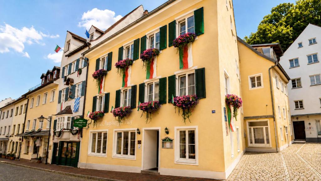 a yellow building with flowers on the windows at Stadthotel Augsburger Hof in Landsberg am Lech