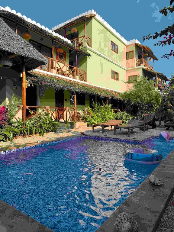 a swimming pool in front of a building at Peace And Color Limited Guest House in Nungwi