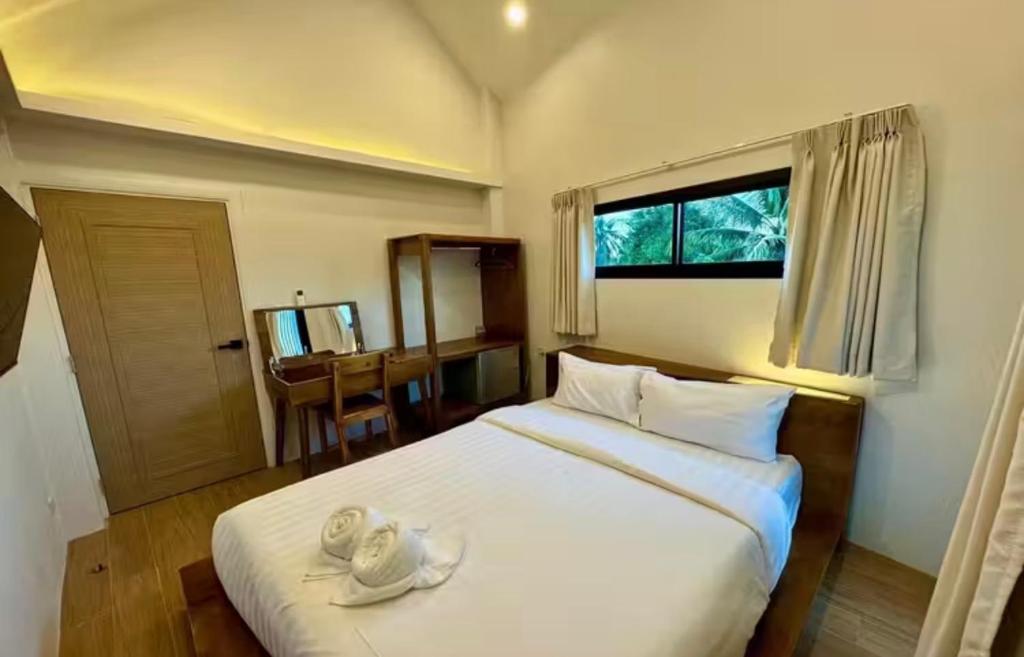 A compact bedroom with a white bed, dressing table and narrow horizontal window.