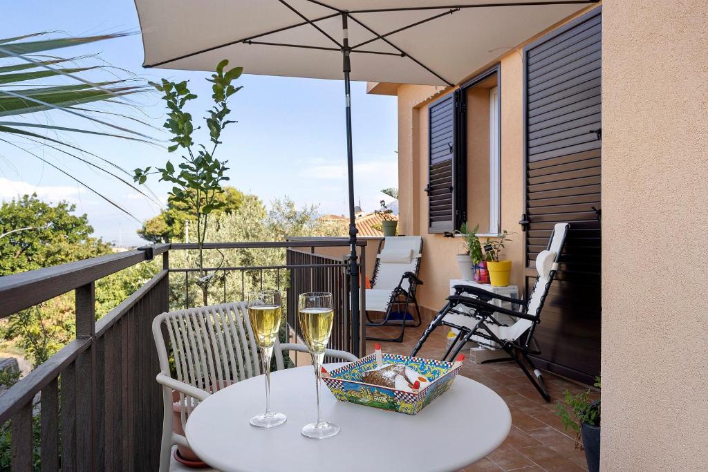 a table with two glasses of wine on a balcony at Sicilian Sea Breeze - Apartment in Bagheria