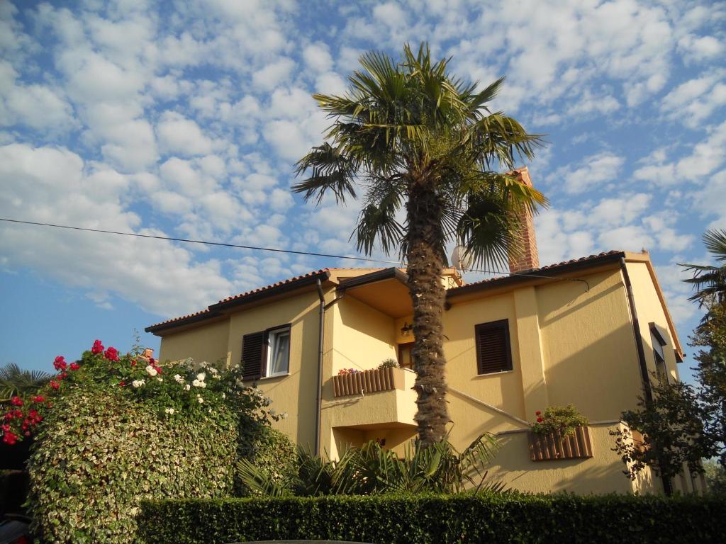 a yellow house with a palm tree in front of it at Apartments Mirella in Novigrad Istria